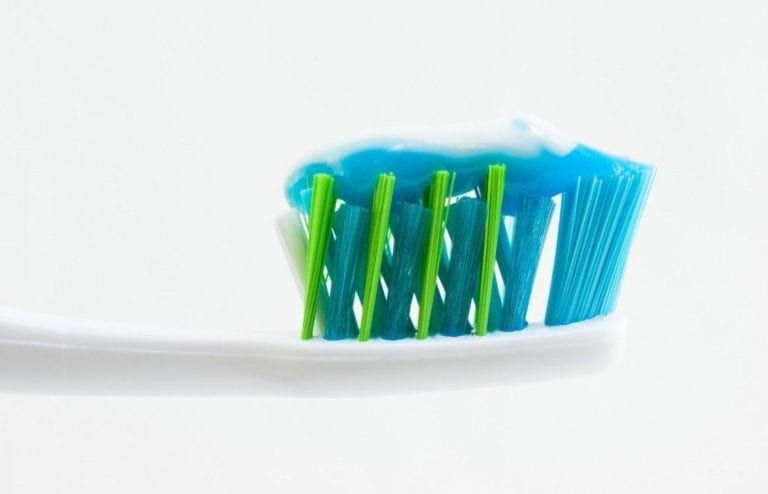 toothpaste on a blue toothbrush with a white background