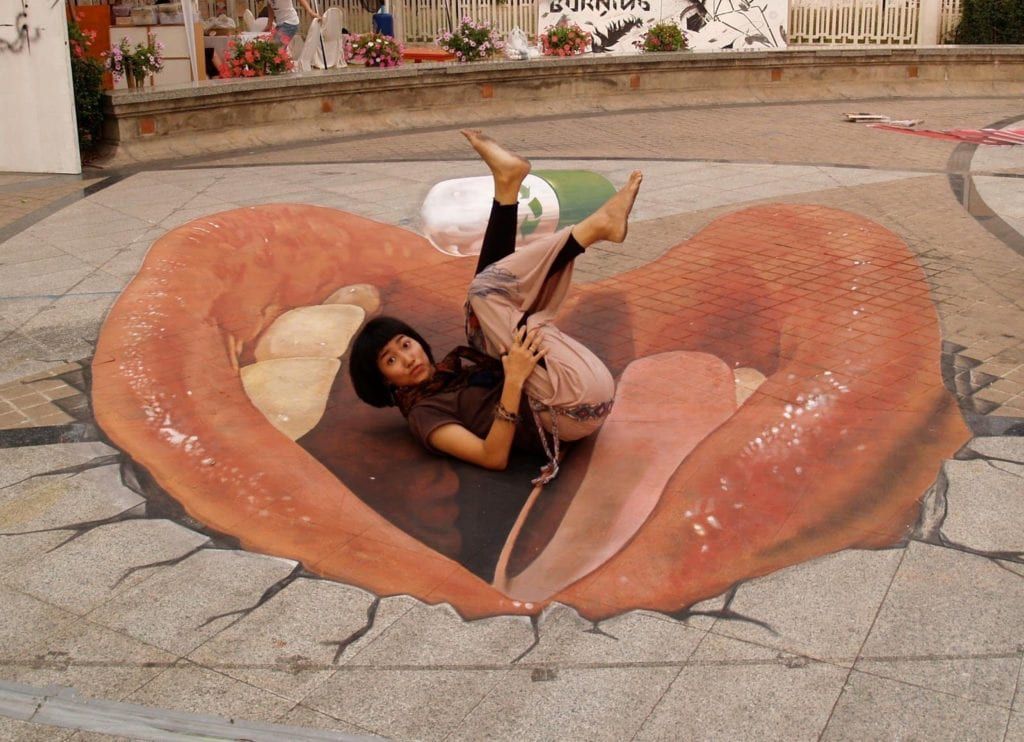 Lips painted on the sidewalk while artist poses above it