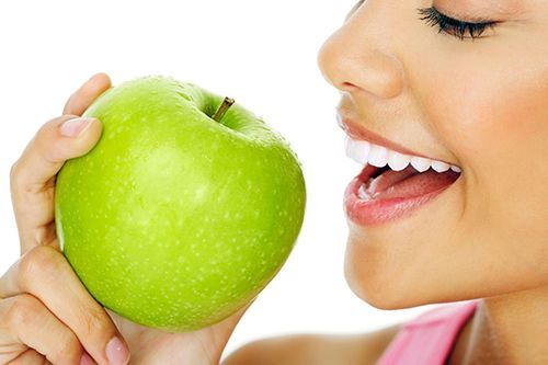woman about to bite a green apple