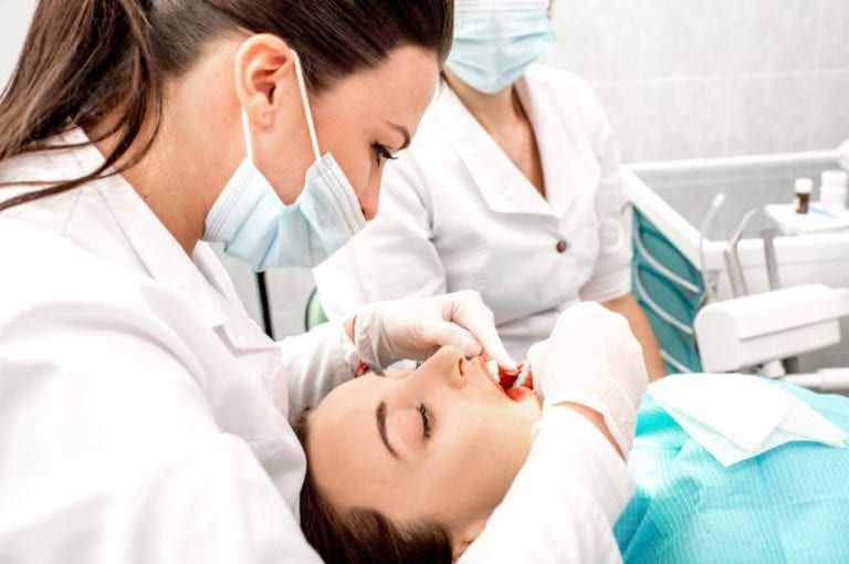 female dentist checking female patient teeth