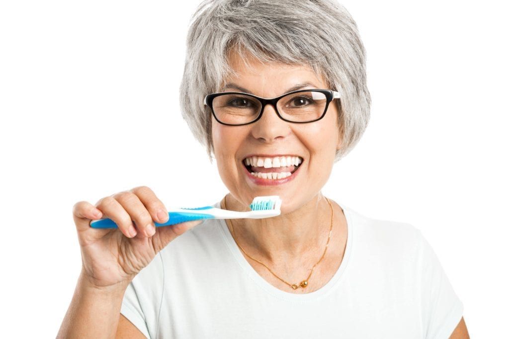 woman showing her teeth while holding a toothbrush