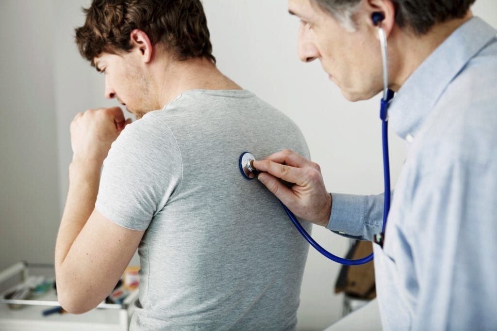 Man coughing and having his doctor listen to his heart