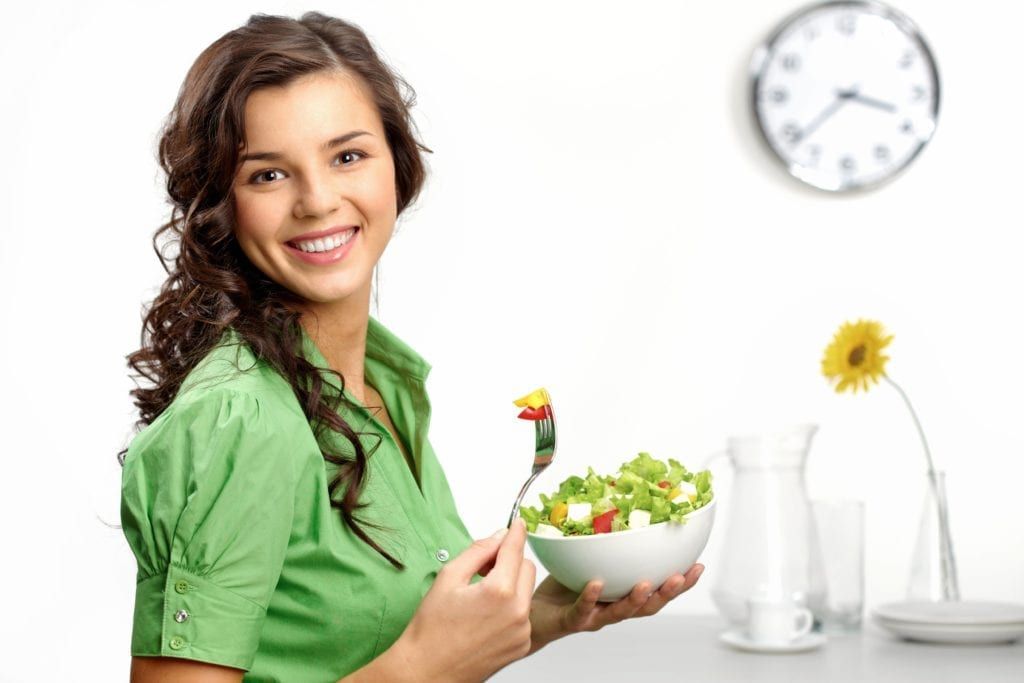 woman smiling and eating a salad